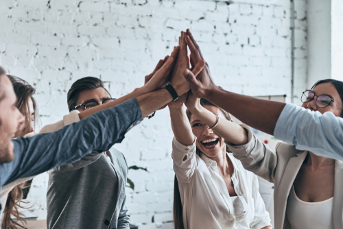 Image of six people high fiving in the air.